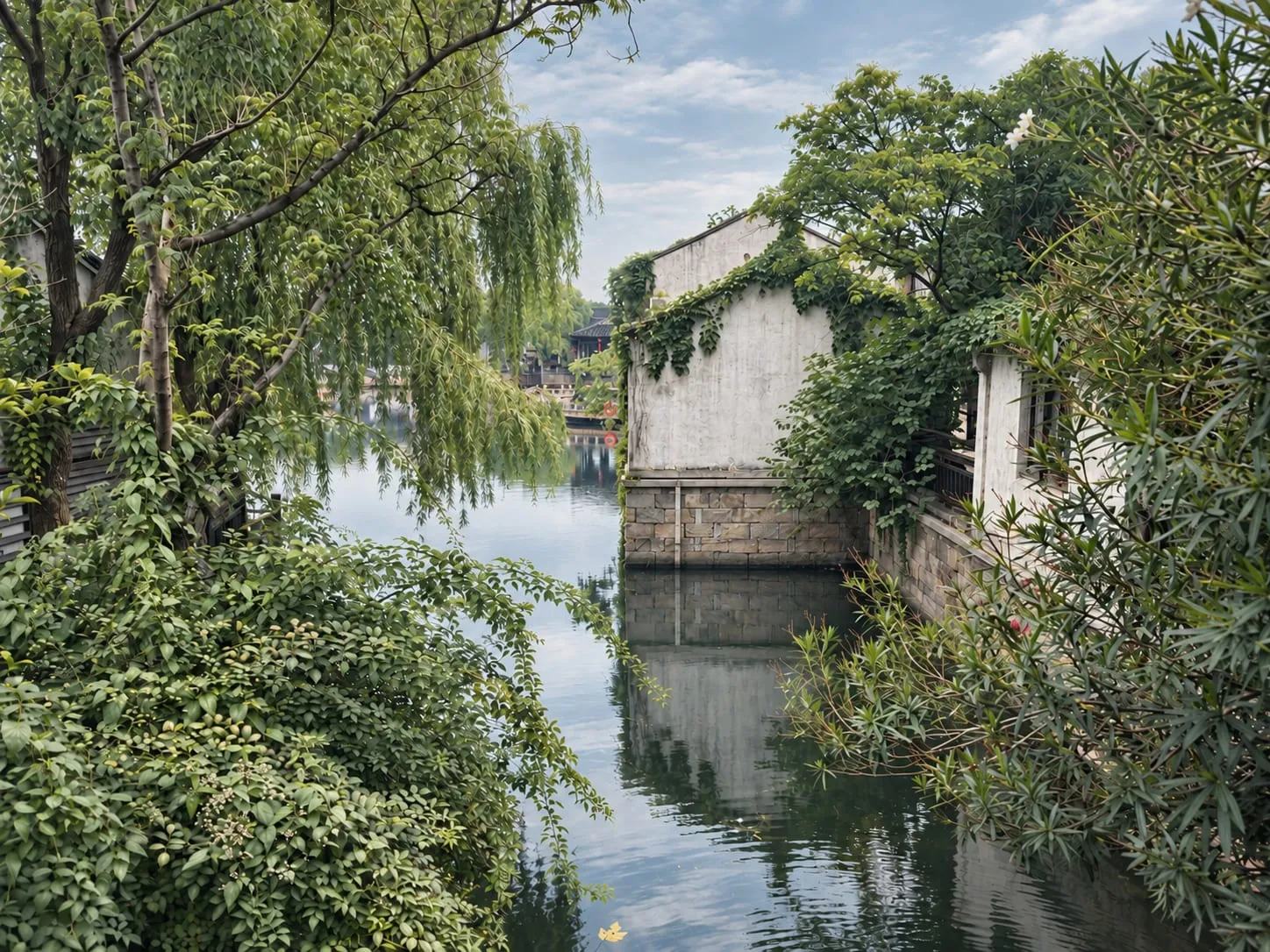 A narrow canal between weeping willows and ivy-covered white walls